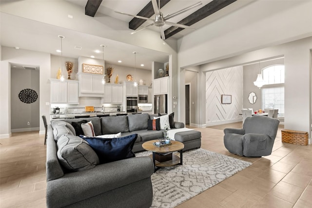 living room with beam ceiling, ceiling fan, and a high ceiling