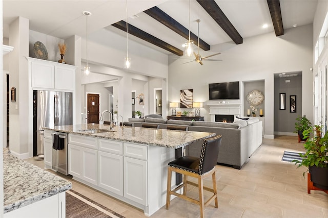 kitchen with white cabinetry, sink, and an island with sink