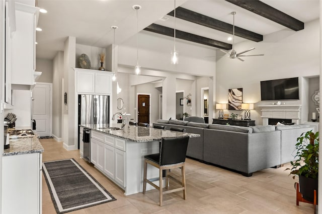 kitchen featuring stainless steel appliances, ceiling fan, sink, white cabinets, and an island with sink