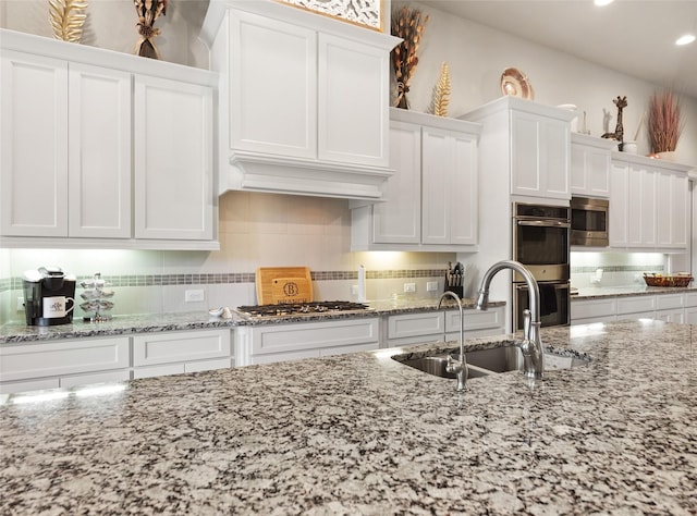 kitchen featuring white cabinets, stainless steel appliances, light stone counters, and sink