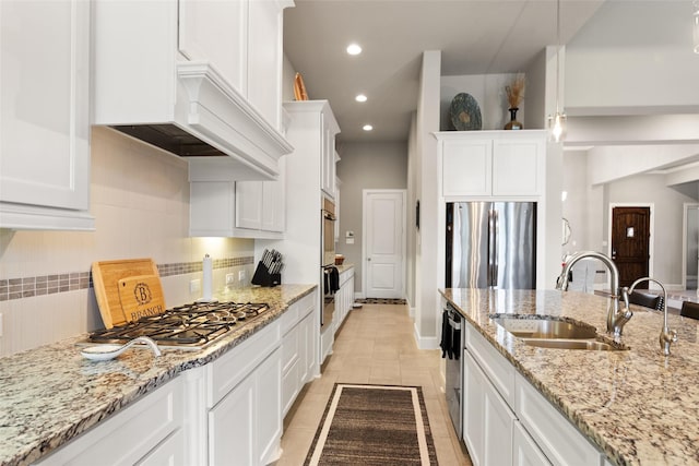 kitchen with light stone countertops, stainless steel appliances, sink, pendant lighting, and white cabinetry