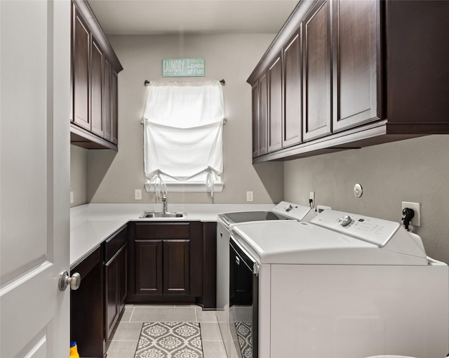 washroom featuring washing machine and dryer, sink, light tile patterned floors, and cabinets