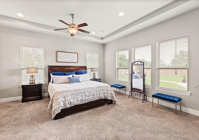 carpeted bedroom featuring a tray ceiling and ceiling fan