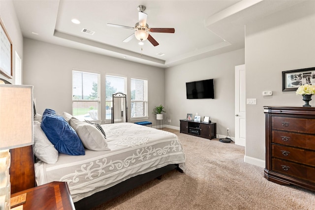 carpeted bedroom featuring a raised ceiling and ceiling fan