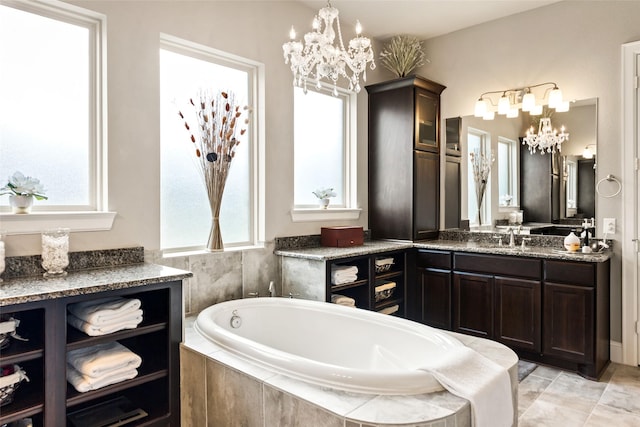 bathroom with vanity, a relaxing tiled tub, plenty of natural light, and an inviting chandelier