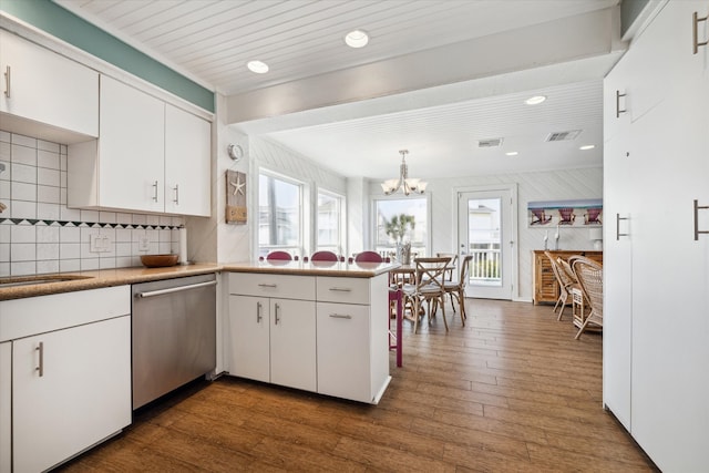 kitchen with an inviting chandelier, dishwasher, backsplash, wood-type flooring, and white cabinets