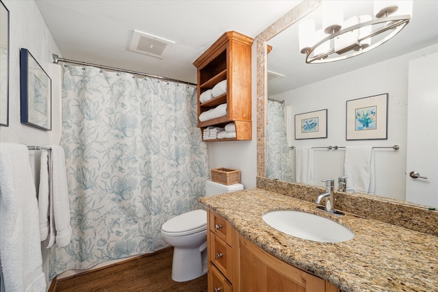 bathroom with wood-type flooring, vanity with extensive cabinet space, a chandelier, and toilet