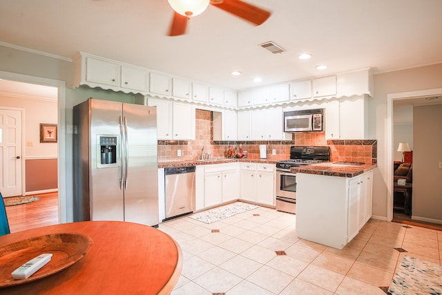 kitchen featuring appliances with stainless steel finishes, white cabinets, backsplash, and ceiling fan