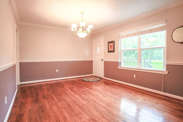 empty room featuring ornamental molding, hardwood / wood-style flooring, and a chandelier