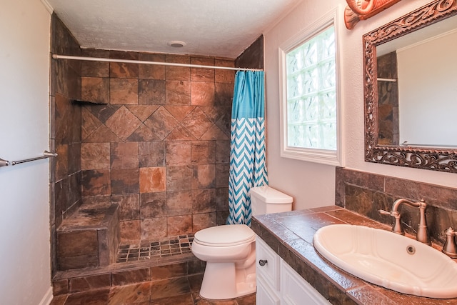 bathroom with tile flooring, walk in shower, a textured ceiling, toilet, and vanity