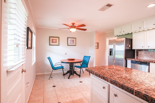 kitchen featuring stainless steel appliances, white cabinets, backsplash, ceiling fan, and light tile floors