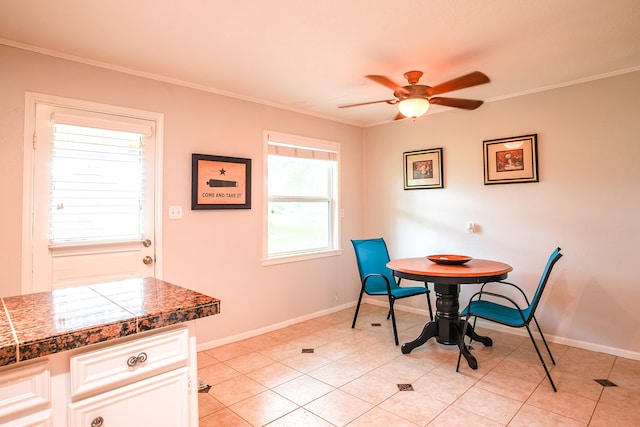 tiled dining space featuring ceiling fan and crown molding