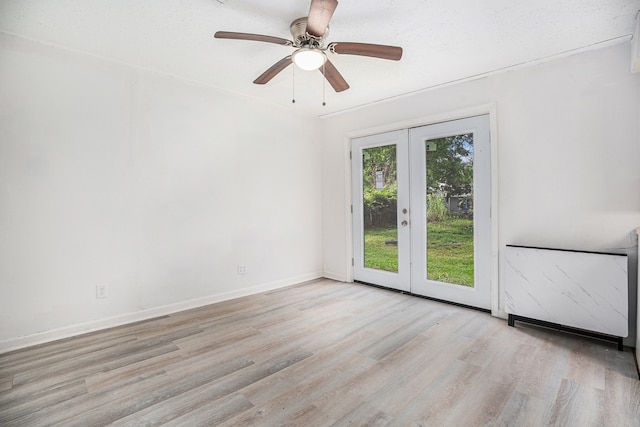 unfurnished room featuring ceiling fan, light wood-type flooring, a textured ceiling, and french doors