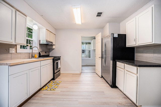 kitchen featuring appliances with stainless steel finishes, white cabinetry, a healthy amount of sunlight, and sink