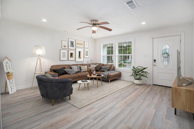 living room with ceiling fan, light wood-type flooring, and a textured ceiling