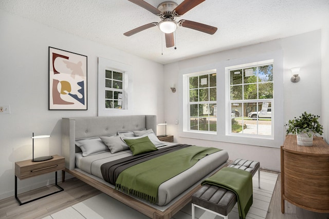 bedroom featuring ceiling fan, light hardwood / wood-style floors, and a textured ceiling