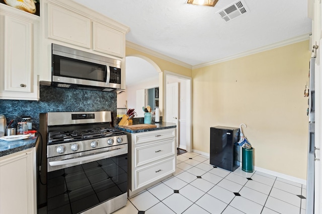 kitchen featuring appliances with stainless steel finishes, tasteful backsplash, light tile patterned floors, and ornamental molding