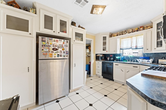 kitchen with decorative backsplash, white cabinetry, black dishwasher, and stainless steel refrigerator