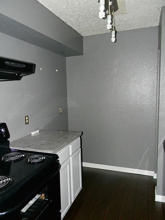 kitchen with black electric range, white cabinetry, a textured ceiling, dark hardwood / wood-style floors, and extractor fan