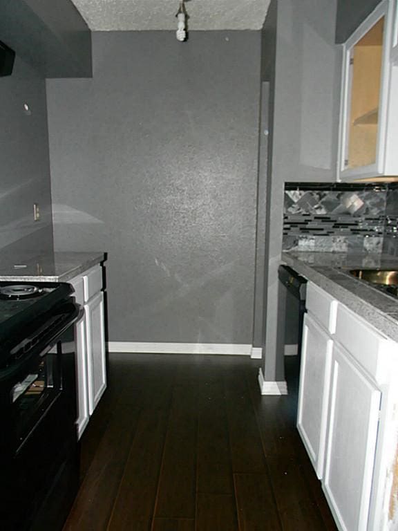 kitchen with dark hardwood / wood-style flooring, black electric range, tasteful backsplash, white cabinets, and a textured ceiling