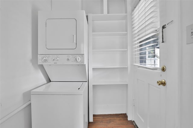 clothes washing area featuring stacked washer and clothes dryer and hardwood / wood-style flooring