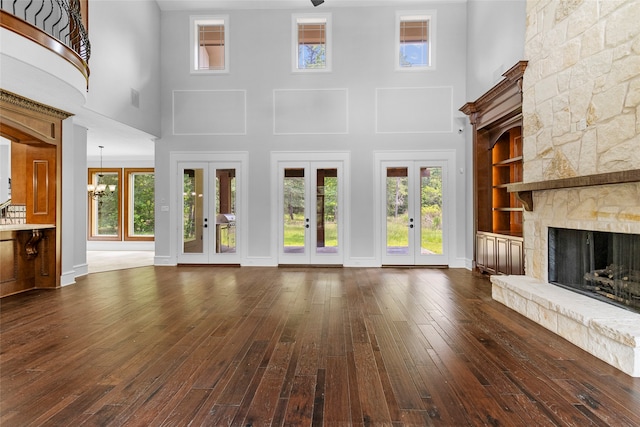 unfurnished living room with a towering ceiling, french doors, and a fireplace