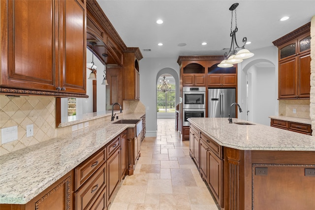 kitchen featuring an island with sink, stainless steel appliances, backsplash, and sink