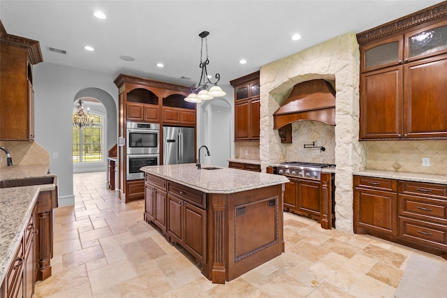 kitchen with a kitchen island with sink, tasteful backsplash, pendant lighting, and stainless steel appliances