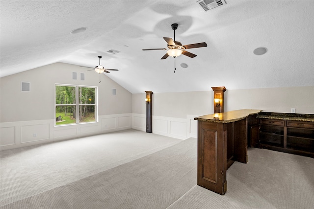 additional living space featuring a textured ceiling, ceiling fan, vaulted ceiling, and light colored carpet