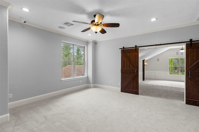 empty room with a healthy amount of sunlight, carpet, a barn door, and ceiling fan