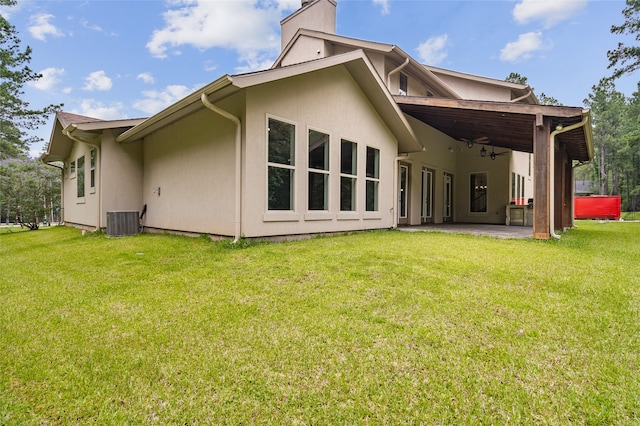 back of property with a patio, a lawn, and central AC