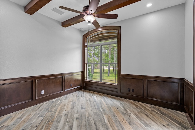 spare room with ceiling fan, light wood-type flooring, and beam ceiling