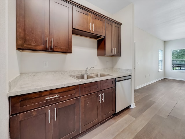 kitchen with light stone countertops, light hardwood / wood-style flooring, dishwasher, dark brown cabinetry, and sink