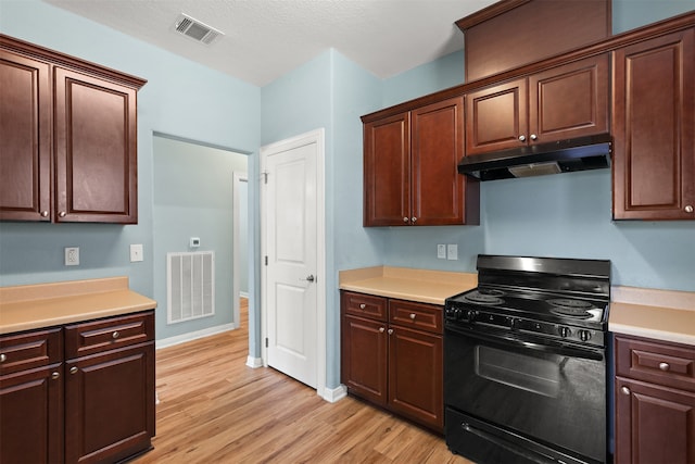 kitchen with black range, light hardwood / wood-style floors, and a textured ceiling