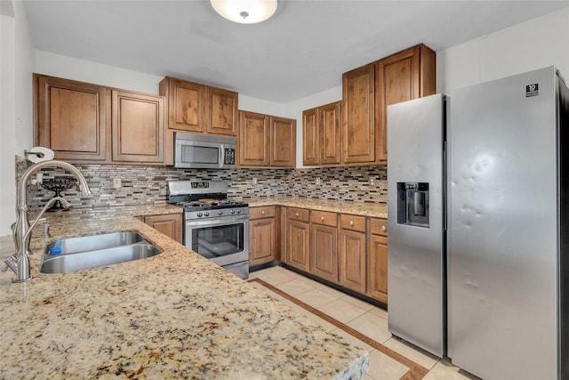 kitchen with sink, light stone counters, light tile patterned floors, appliances with stainless steel finishes, and backsplash