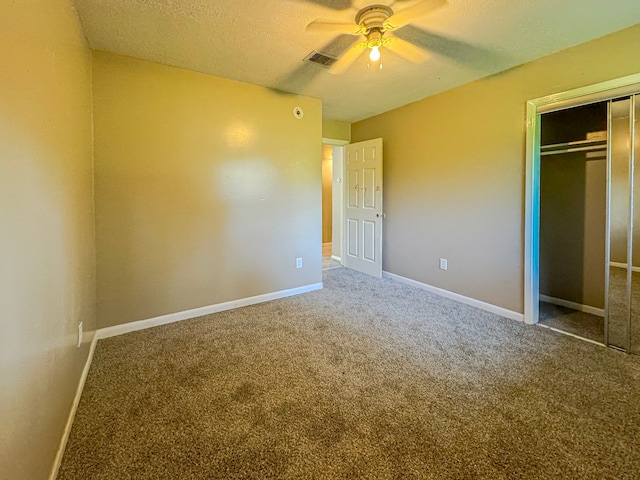 unfurnished bedroom featuring ceiling fan, a closet, a textured ceiling, and carpet flooring