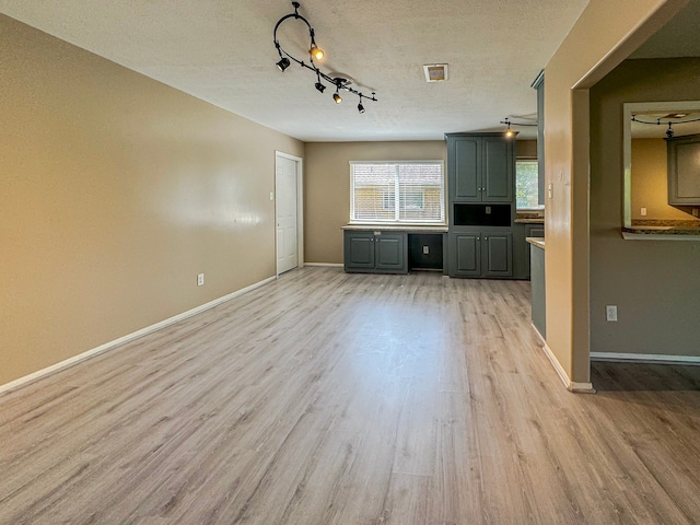 unfurnished living room with a textured ceiling, light hardwood / wood-style flooring, and rail lighting