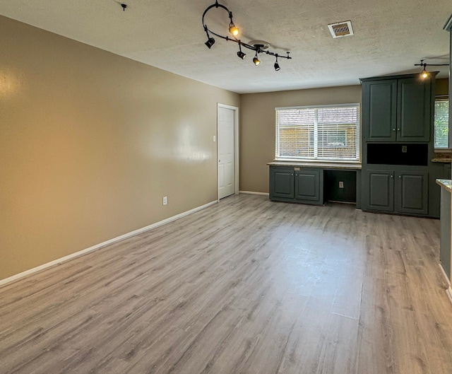 unfurnished living room featuring a textured ceiling, light wood-type flooring, and rail lighting