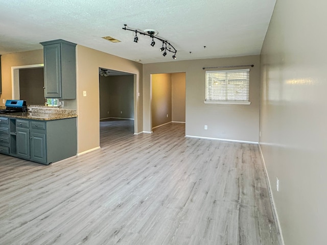 interior space with light hardwood / wood-style flooring, a textured ceiling, and rail lighting