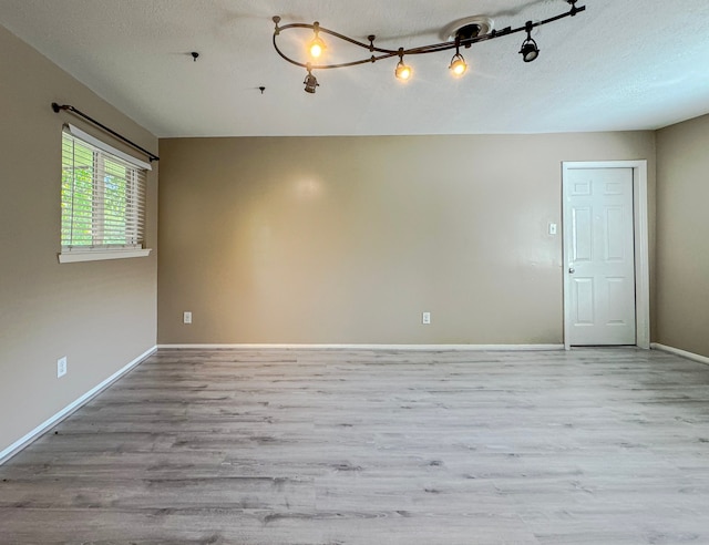 unfurnished room featuring hardwood / wood-style flooring, a textured ceiling, and rail lighting