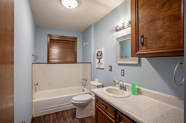 bathroom featuring vanity with extensive cabinet space, a textured ceiling, hardwood / wood-style flooring, and toilet