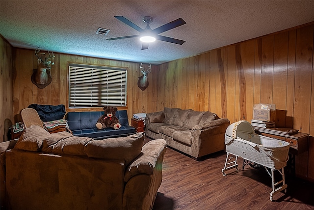 living room with a textured ceiling, wood-type flooring, ceiling fan, and wood walls