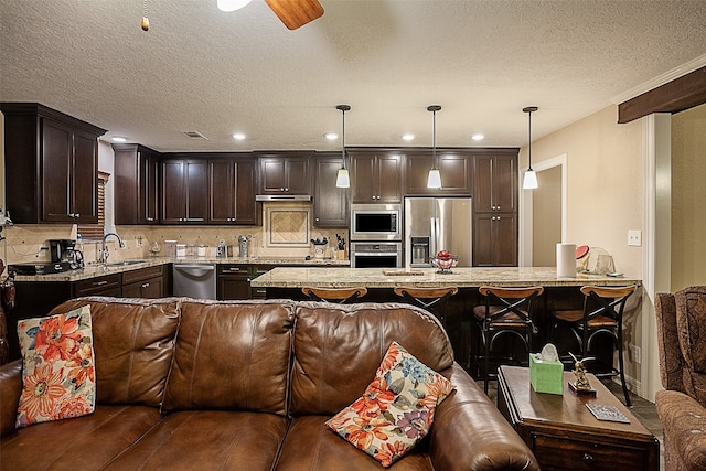 kitchen with decorative light fixtures, appliances with stainless steel finishes, sink, and kitchen peninsula