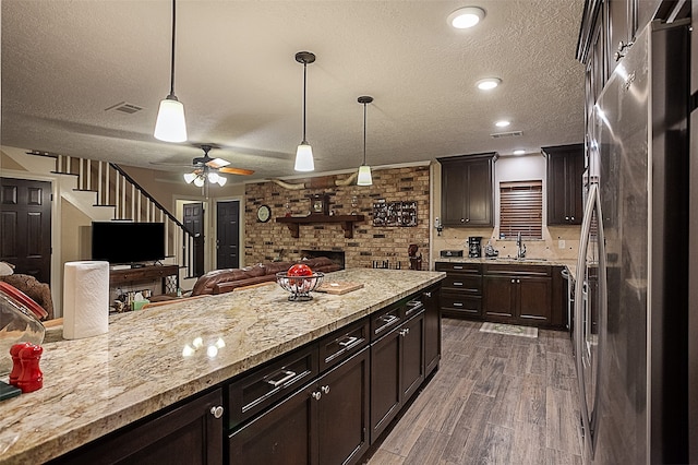 kitchen with brick wall, dark hardwood / wood-style flooring, stainless steel refrigerator, pendant lighting, and ceiling fan