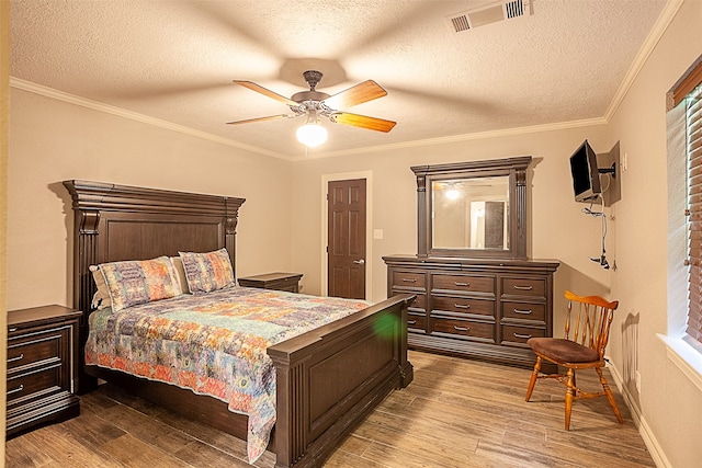 bedroom with a textured ceiling, ceiling fan, hardwood / wood-style floors, and ornamental molding