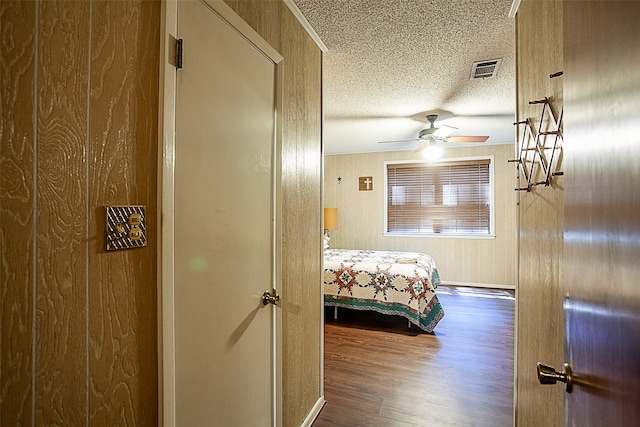 bedroom with a textured ceiling, ceiling fan, and dark hardwood / wood-style flooring