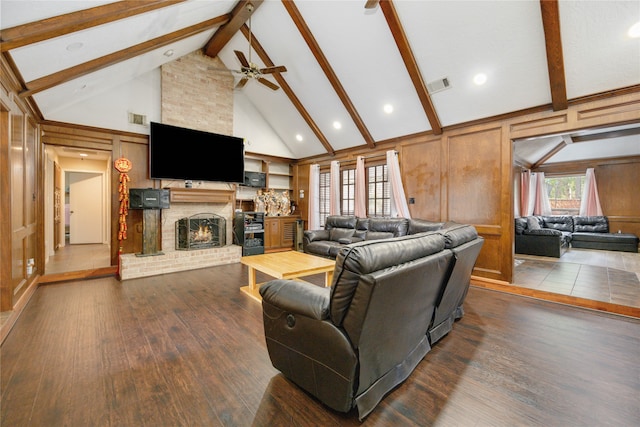 living room featuring dark hardwood / wood-style floors, beamed ceiling, ceiling fan, and a fireplace