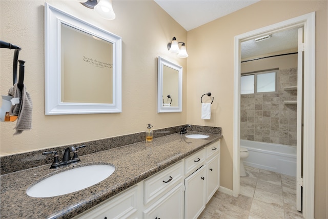 full bathroom featuring dual bowl vanity, tiled shower / bath, toilet, and tile floors