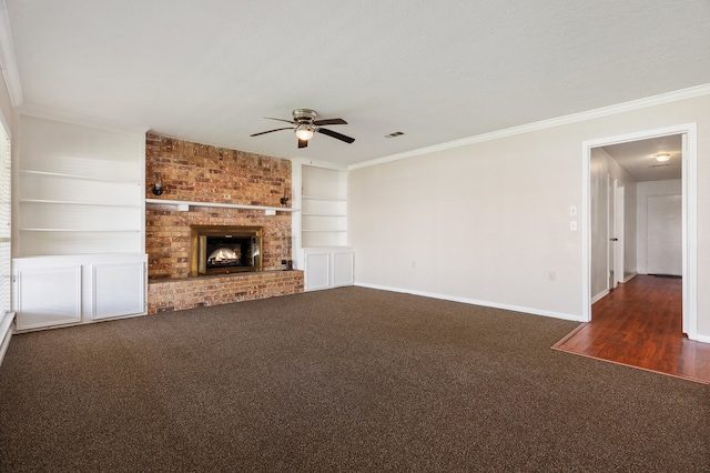 unfurnished living room with ceiling fan, dark colored carpet, brick wall, ornamental molding, and a fireplace