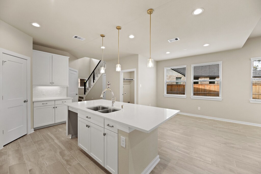 7823 Open Point Dr, Cypress, TX 77433 - kitchen featuring an island with sink, sink, plenty of natural light, and white cabinetry